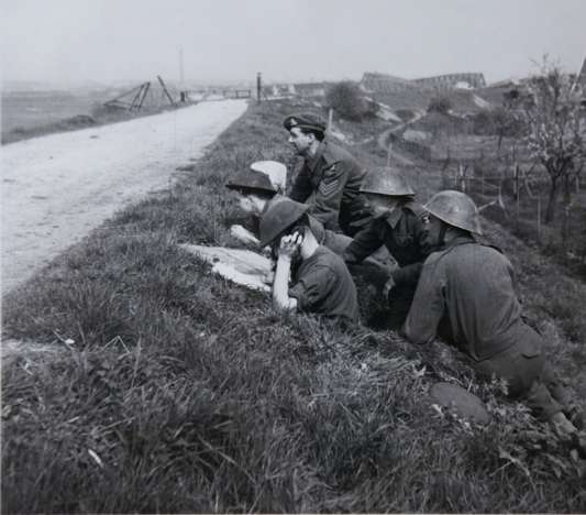 Geallieerde militairen kijken vanuit Westervoort uit over de IJssel en Arnhem. 