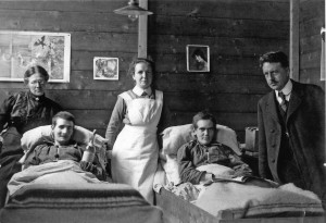 Twee zieke krijgsgevangenen, een verpleegster (midden), directeur dominee G.J.B. Stork (rechts) en zijn echtgenote (links) in de ziekenboeg van het quarantainekamp in 1918.