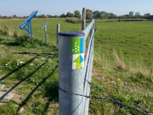 Hek om weiland met sticker van het klompenpad