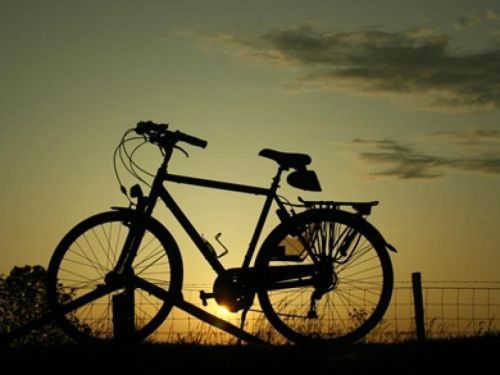 Silhouette van een fiets tegen ondergaande zon