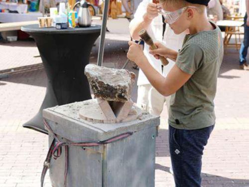 Jongen bewerkt steen met een beitel en hamer